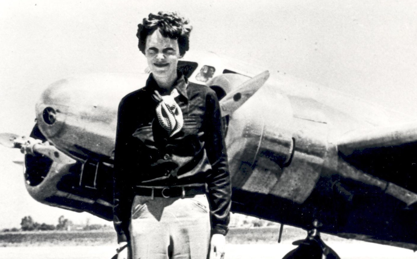 Amelia Earhart standing in front of her plane