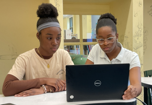 Assistant Instructor Makayla guiding a beginner student through basic coding principles on a laptop